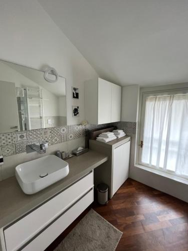 un bagno con lavandino, specchio e finestra di La Rocca Luxury Apartment a Parma