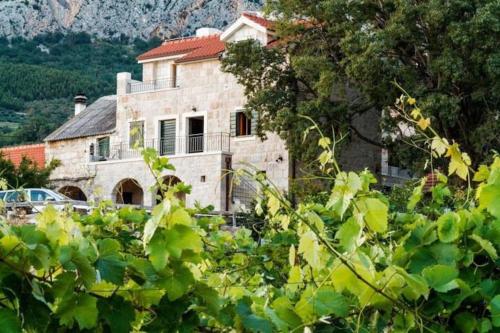 an old stone house with a mountain in the background at Charming stone villa Silva in Tučepi