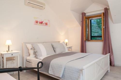 a white bedroom with a bed and a window at Charming stone villa Silva in Tučepi
