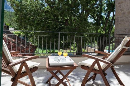 two chairs and a table with two glasses of wine at Charming stone villa Silva in Tučepi