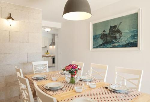 a dining room with a table with chairs and a painting at Charming stone villa Silva in Tučepi