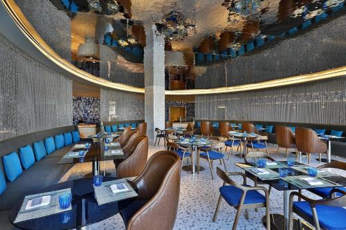 a restaurant with tables and chairs and a large mirror at W Muscat in Muscat