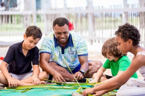 a man and three children playing with a piece of paper at Sheraton Fiji Golf & Beach Resort in Denarau