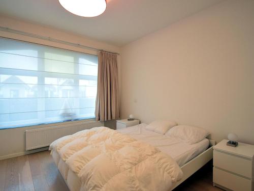 ein Schlafzimmer mit einem Bett und einem großen Fenster in der Unterkunft Hofstad Verde 0001apartment on the ground floor in De Haan