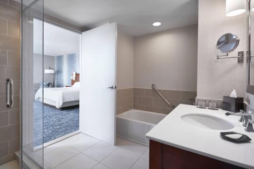 a bathroom with a sink and a shower and a bed at The Westin Virginia Beach Town Center in Virginia Beach