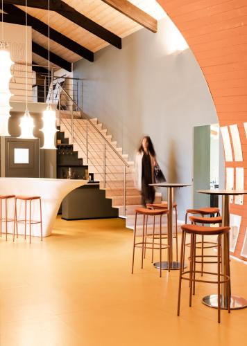 a woman walking through a room with tables and stools at Sella&Mosca Casa Villamarina in Alghero