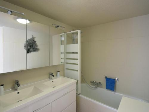 uma casa de banho com um lavatório, um espelho e um chuveiro em Dante 0103 furnished apartment with 2 bedrooms em De Haan
