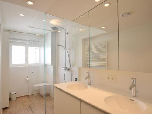 een badkamer met 2 wastafels en een douche met een spiegel bij Golf 0301 apartment with modern kitchen by the sea in De Haan