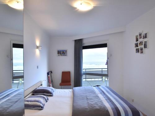 een slaapkamer met een bed en uitzicht op de oceaan bij James Ensor 0102 south-facing corner apartment in De Haan