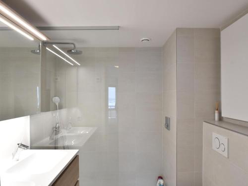 een witte badkamer met een wastafel en een douche bij James Ensor 0102 south-facing corner apartment in De Haan