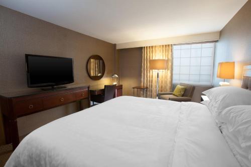 um quarto de hotel com uma cama e uma televisão de ecrã plano em Sheraton Pittsburgh Airport Hotel em Coraopolis