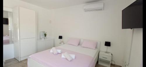 a white bedroom with a white bed with pink pillows at Apartman Punta Radman in Petrcane