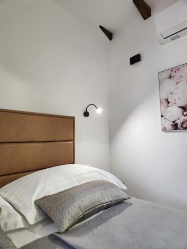 a white bedroom with a bed with a wooden headboard at Rio Luxury Rooms in Split