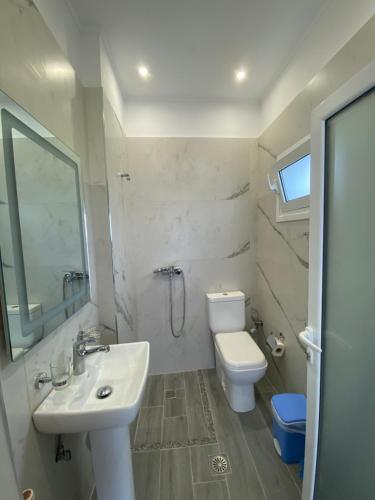 a white bathroom with a sink and a toilet at Wave n' Sea Apartments in Himare