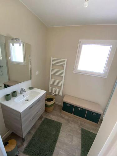 une salle de bain avec un lavabo, un miroir et une fenêtre dans l'établissement Wimereux proche plage et centre, à Wimille