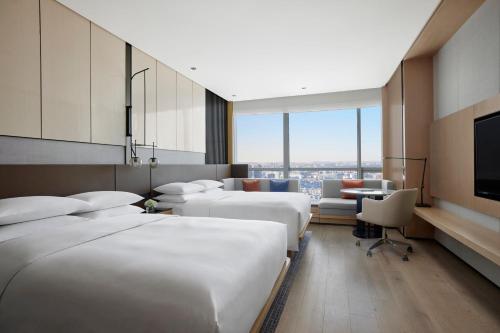 a hotel room with four beds and a television at Shenyang Marriott Hotel in Shenyang