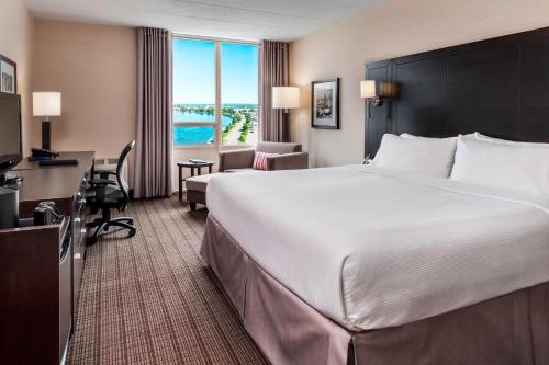 スーセントマリーにあるDelta Hotels by Marriott Sault Ste. Marie Waterfrontの大きなベッドとデスクが備わるホテルルームです。