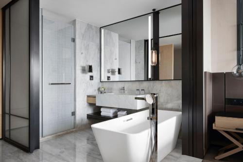 a bathroom with a tub and a sink and a mirror at Shenyang Marriott Hotel in Shenyang