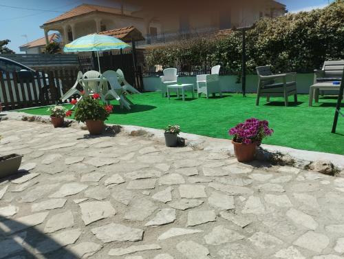 een patio met groen gras en stoelen en een parasol bij Oasi hause in Castel Volturno