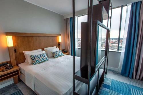 um quarto de hotel com uma cama grande e uma janela em Courtyard by Marriott Katowice City Center em Katowice