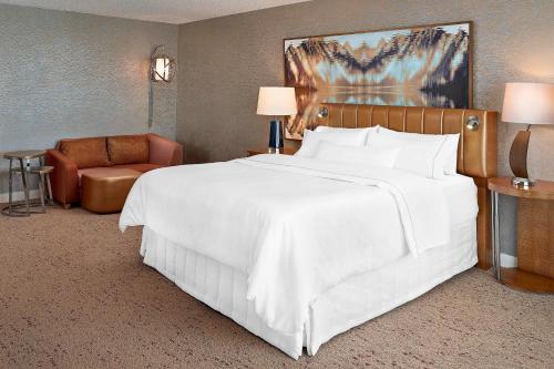 - une chambre avec un grand lit blanc et une chaise dans l'établissement The Westin Edmonton, à Edmonton
