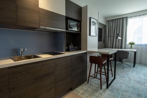 a kitchen with wooden cabinets and a table with stools at Residence Inn by Marriott Toulouse-Blagnac in Blagnac