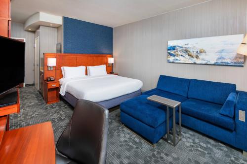 a hotel room with a bed and a blue couch at Courtyard by Marriott Santa Ana Orange County in Santa Ana