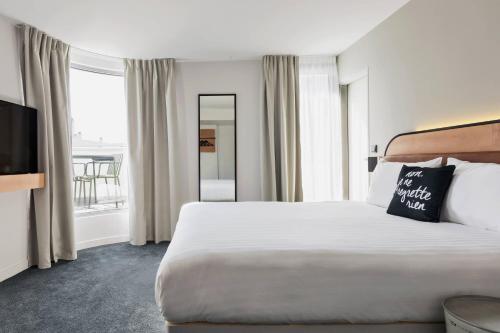 パリにあるMoxy Paris Bastilleの大きなベッドと大きな窓が備わるホテルルームです。
