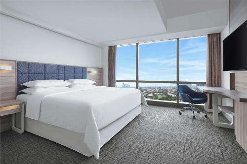 a hotel room with a bed and a desk and window at Four Points by Sheraton Surabaya, Pakuwon Indah in Surabaya