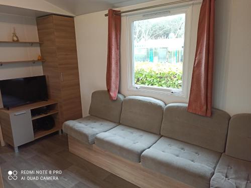 a living room with a couch and a window at MOBILHOME 3 CHBRES 2 SDE 2 WC LV LL TV CLIM TOUT CONFORT in Gastes
