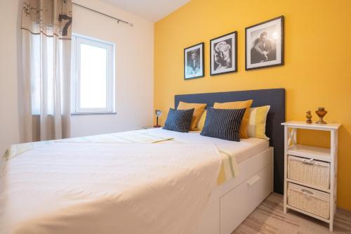 a bedroom with a large white bed with yellow walls at Sea View Apartment Ana in Podstrana