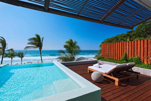 a swimming pool sitting on a deck next to the beach at W Punta de Mita in Punta Mita