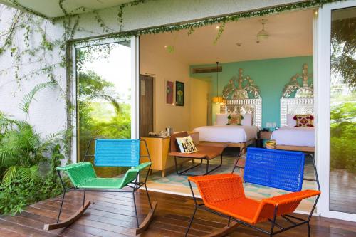 a room with colorful chairs and a bedroom at W Punta de Mita in Punta Mita