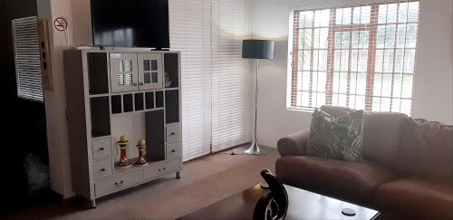 a living room with a couch and a television at Shark Cove House in Kleinbaai