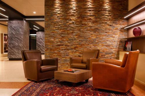 a lobby with three chairs and a brick wall at Four Points by Sheraton Padova in Padova