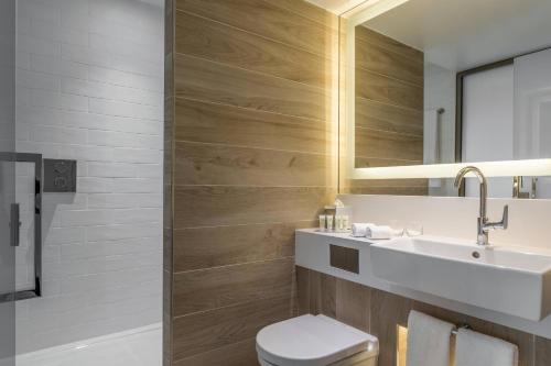 a bathroom with a toilet and a sink and a mirror at Courtyard by Marriott Paris Gare de Lyon in Paris