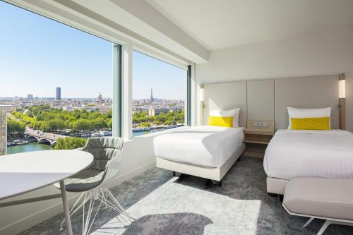 パリにあるCourtyard by Marriott Paris Gare de Lyonのベッド2台とデスクが備わるホテルルームです。