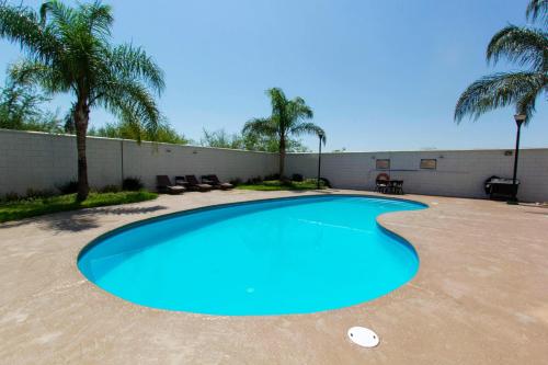 a large blue swimming pool in a yard with palm trees at Wyndham Garden Monterrey Aeropuerto in Monterrey