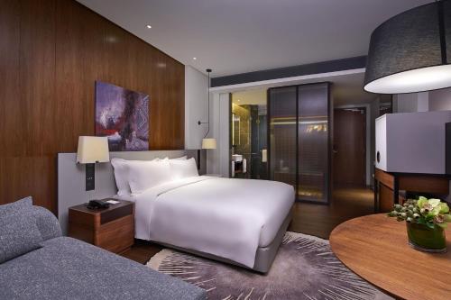 八打靈再也的住宿－Le Meridien Petaling Jaya，卧室配有一张白色的大床和一张沙发。