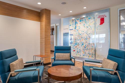 a waiting room with blue chairs and a map at TownePlace Suites by Marriott Indianapolis Airport in Indianapolis