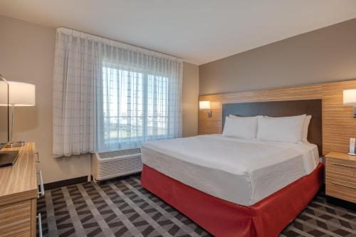 a hotel room with a large bed and a window at TownePlace Suites by Marriott Indianapolis Airport in Indianapolis