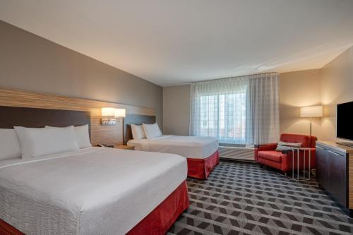 a hotel room with two beds and a television at TownePlace Suites by Marriott Indianapolis Airport in Indianapolis