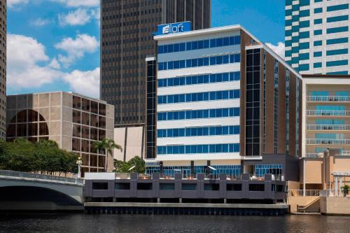 ein Gebäude mit einem Schild darüber neben einem Fluss in der Unterkunft Aloft - Tampa Downtown in Tampa