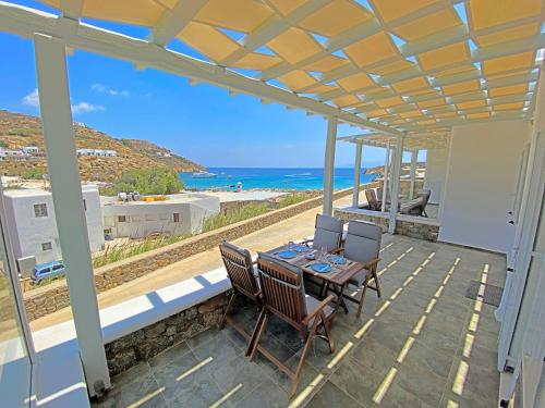 a patio with a table and chairs and the ocean at 1Path Wave Mykonos Super Paradise Beach House in Mýkonos City