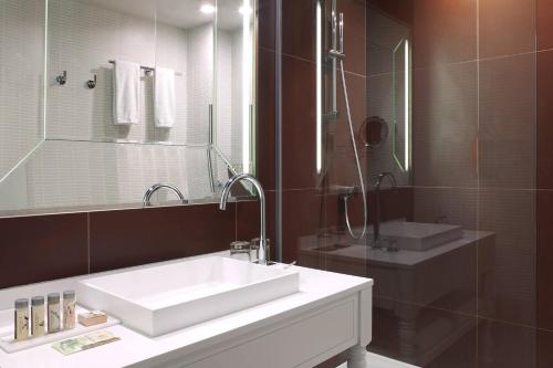 a bathroom with a white sink and a mirror at Renaissance Paris Hippodrome de St. Cloud Hotel in Rueil-Malmaison