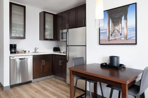 a kitchen with a wooden table and a refrigerator at Residence Inn by Marriott Los Angeles Redondo Beach in Redondo Beach