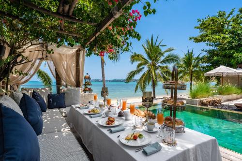a table with food next to a swimming pool at ODYSSEY - Luxury Beachfront Mansion - in Koh Samui