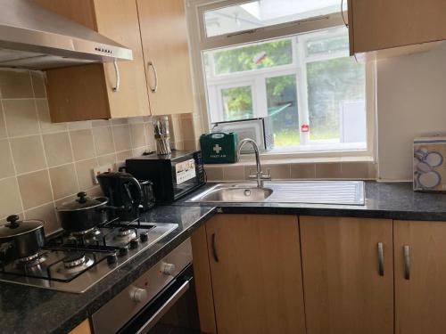 a kitchen with a stove and a sink and a window at Hallykins in Erith