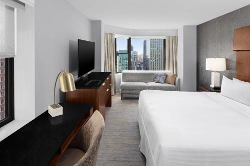 ニューヨークにあるウェスティン ニューヨーク グランドセントラルの大きなベッドとソファが備わるホテルルームです。