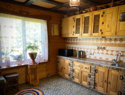 a kitchen with wooden cabinets and a sink and a window at Гостинний двір in Oryavchyk